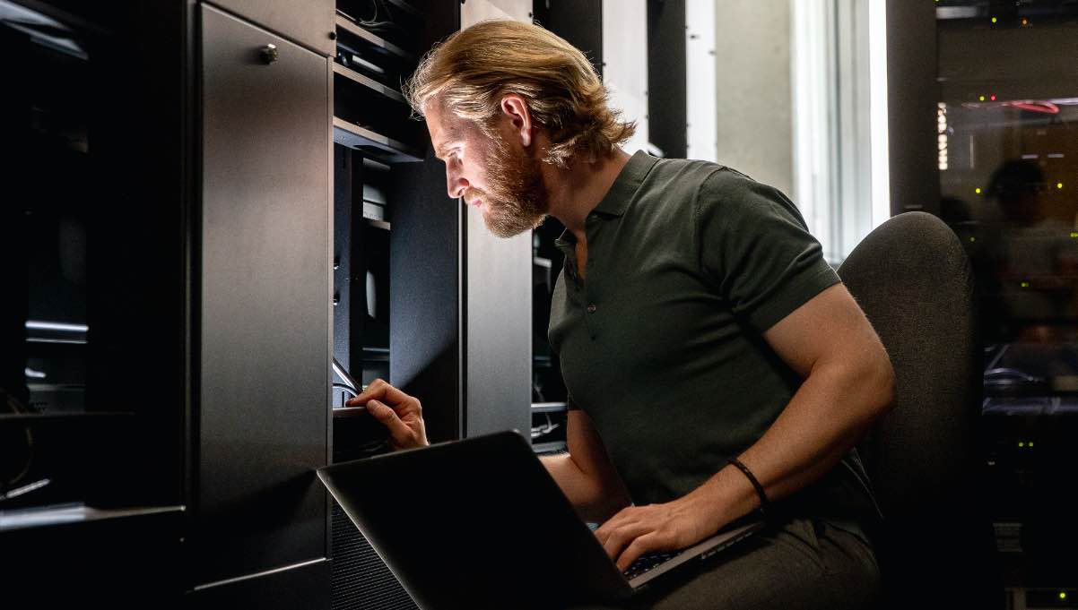 Man holding laptop examines data server