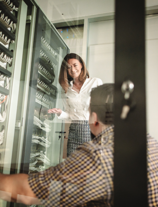 2 people talk in front of server racks