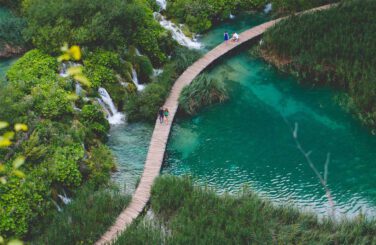 Couples walk across long bridge over blue water