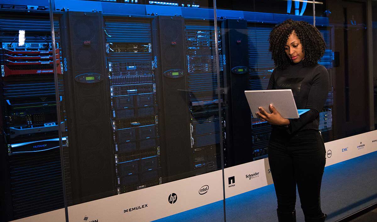 Woman working on laptop near modern looking data center servers