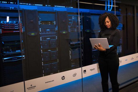 Woman working on laptop near modern looking data center servers